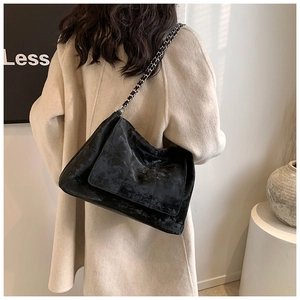 Close-up of quilted black tote bag featuring chain strap and textured matte leather finish