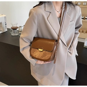 Détail d'un sac besace marron vintage en cuir texturé avec fermoir doré en demi-lune