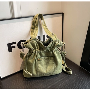 Close-up of green denim bucket bag featuring a drawstring closure and front patch pocket