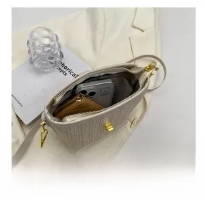 Internal view of beige woven bucket bag showing storage space for phone and wallets