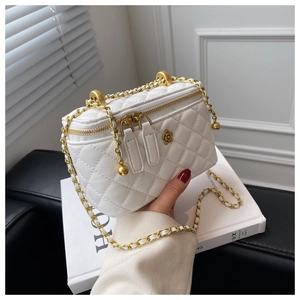 Detailed view of white quilted bucket bag featuring gold flower logo and chain strap