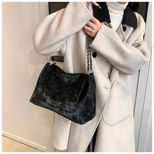 Model wearing a large black matte tote bag with quilted pattern and silver chain strap