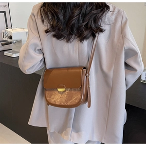 Détail du sac besace marron avec empiècement marbré et boucle dorée porté à l'épaule