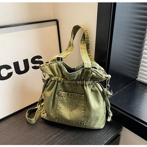 Detail view of the drawstring closure and vintage green denim texture on the bucket bag