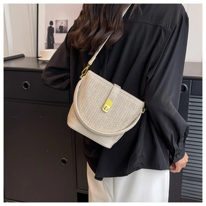 Detail of V-shaped straw weave texture and gold metal turn-lock on the bucket bag