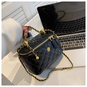 Close-up of black quilted vanity bag with gold chain strap and metal floral charm
