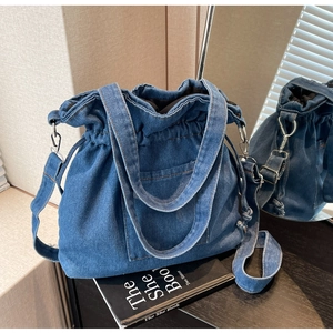 Detailed view of blue denim drawstring bucket bag with silver metal hooks and handles