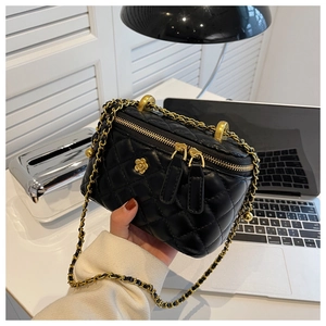 Detail of black quilted leather bucket bag with gold floral clasp and chain strap