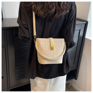 Detail showing the textured woven pattern and elegant gold twist lock of the cream bucket bag