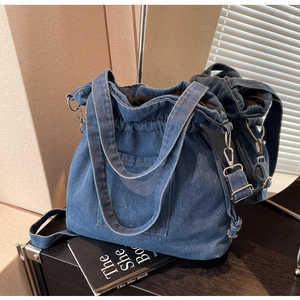 Close-up of blue denim bucket bag with drawstring closure and stylish mirror reflection