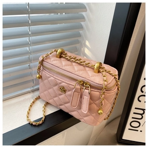 Detail view of pink quilted bucket bag with gold chain strap and floral accent