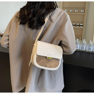Détail du sac selle bicolore avec boucle en métal sur l'épaule du mannequin