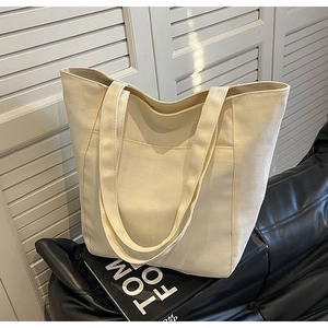 Detalle del bolso tote de lona grande con bolsillo frontal sobre superficie negra