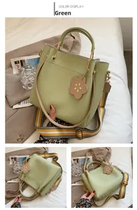 Detail view of light green tote bag with metallic handles and decorative flower charm