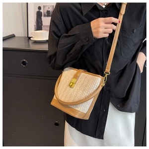 Elegant woven bucket bag with brown leather trim held by model in a minimalist setting