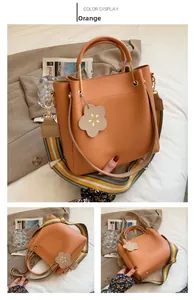 Detail of orange bucket bag with metallic handle and floral charm on white bedding