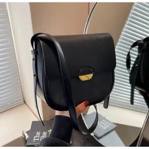 Détail d'un sacoche selle en cuir noir avec fermoir doré et bandoulière ajustable