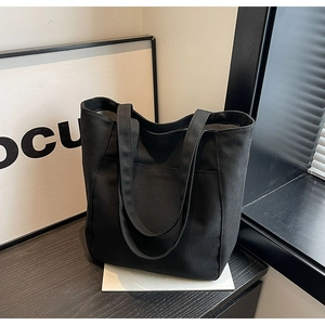 Detalle de bolso tote de lona negra sobre superficie de madera para el uso diario