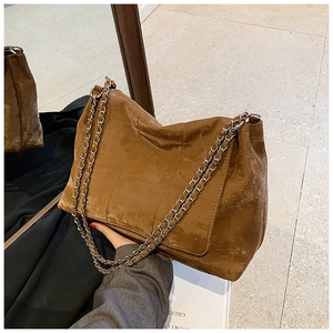 Macro view of vintage brown quilted leather tote with silver chain strap and texture