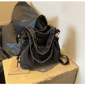 Detail view of washed denim bucket bag with drawstring closure and metal hardware