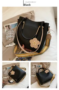 Detail of black leather bucket bag featuring striped strap and floral charm accessory