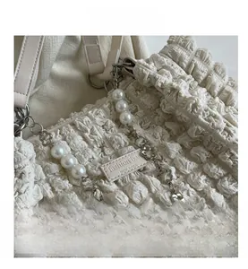 Detail of white pleated tote bag featuring pearl flower chain and fashion bag logo