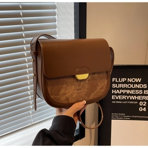 Détail d'un sac besace vintage marron avec boucle dorée et surpiqûres en cuir texturé