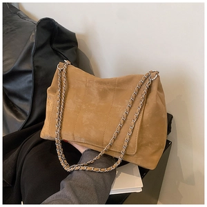 Detail of camel quilted tote bag featuring metal chain strap and matte suede texture