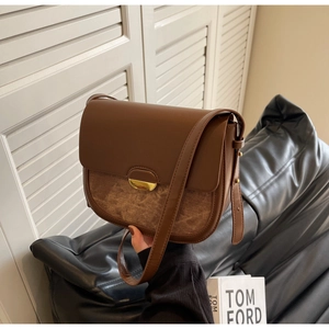 Détail du sac besace en cuir marron avec boucle dorée en croissant et rabat de fermeture