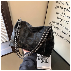 Detail of black quilted tote bag with matte texture and metallic silver chain strap
