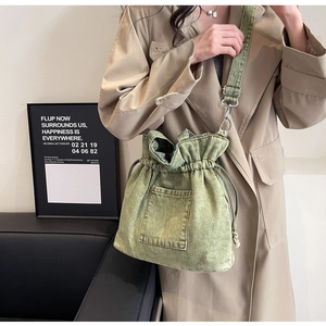 Detail of army green denim bucket bag featuring drawstring closure and front pocket