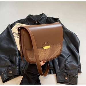 Gros plan du sac besace vintage marron montrant les coutures et le fermoir doré