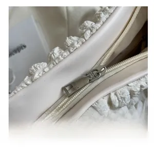 Close-up of a smooth silver zipper on a beige textured bubble fabric shoulder bag