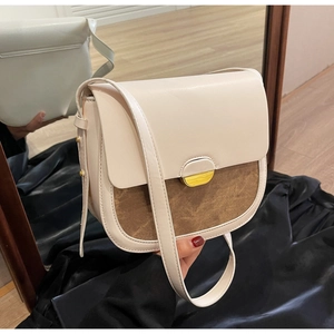 Détail d'un sac besace rétro en cuir crème avec empiècements marron et finitions dorées élégantes