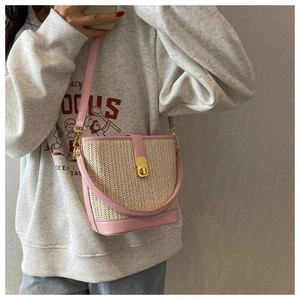 Detail of pink woven bucket bag featuring gold metal clasp and premium leather trim