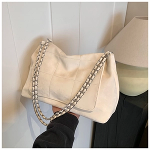 Close-up of white quilted tote bag with silver chain strap and matte suede texture