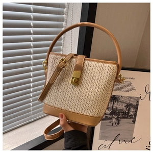 Detailed close-up of woven bucket bag featuring beige herringbone pattern and leather trim
