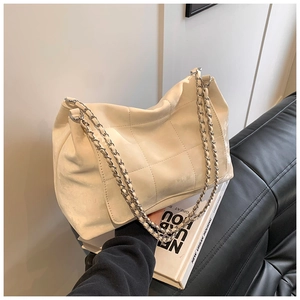 Detail of cream quilted tote bag featuring silver chain strap and large capacity