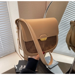 Détail du sac selle rétro avec cuir beige, daim marron et boucle dorée en croissant