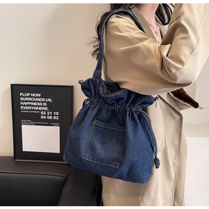 Detailed texture of dark blue denim drawstring bucket bag with decorative stitching