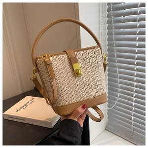 Detail of woven straw bucket bag with faux leather trim and gold metal twist lock