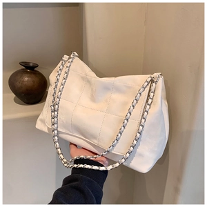 Close-up of white quilted tote bag featuring silver chain strap and faux leather texture