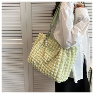 Detail of light green popcorn texture tote bag with pearl heart chain and shoulder strap