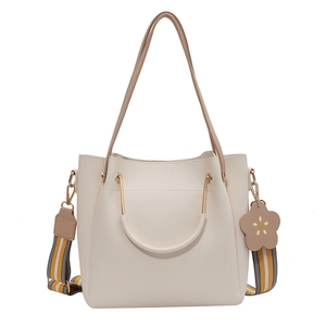Minimalist cream tote bag with metallic handles and colorful striped shoulder strap