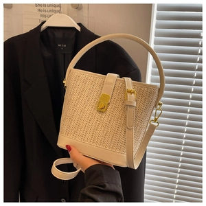 Detailed close-up of woven beige straw bucket bag with gold lock and faux leather trim