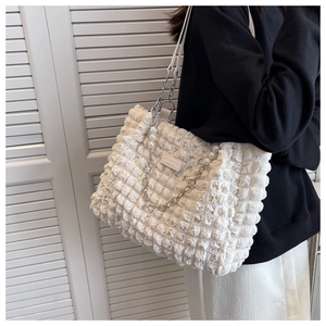 Detail of white bubble texture tote bag featuring elegant pearl and metal chain strap