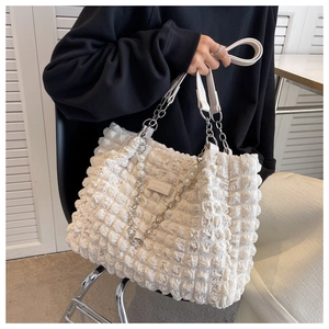Detail of cream bubble texture tote bag with elegant pearl pendant and metal chain straps