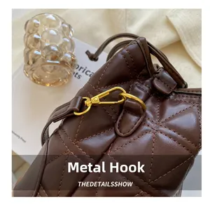 Detailed macro of golden metal hook on dark brown quilted leather bucket bag