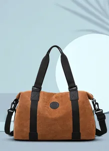 Detail view of large brown travel bag with faux suede texture and black handles