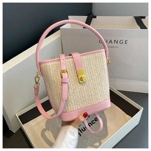 Detail of pink PU leather trim and gold twist lock on the woven straw bucket bag